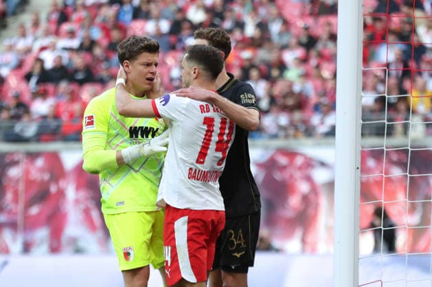 1. Fußball Bundesliga: RB Leipzig - FC Augsburg; 07.03.2026 Christoph Baumgartner (14, RB Leipzig) entschuldigt sich bei Torwart Finn Dahmen (1, FC Augsburg) für seine schmerzhafte Aktion. LEIPZIG, DEUTSCHLAND - MARCH 7: Bundesliga-Spiel RB Leipzig - FC Augsburg in der Red Bull Arena am 25. Spieltag der 1. Bundesliga am March 7, 2026 in Leipzig, Deutschland. DFL REGULATIONS PROHIBIT ANY USE OF PHOTOGRAPHS AS IMAGE SEQUENCES AND OR QUASI-VIDEO.