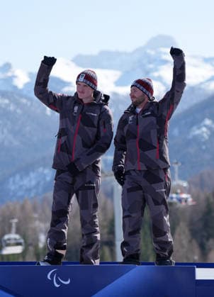 (260308) -- CORTINA D AMPEZZO, March 8, 2026 -- Gold medalist Johannes Aigner (L) of Austria celebrates with his guide Nico Haberl during the awarding ceremony for the para alpine skiing men s downhill vision impaired match at the Milan-Cortina 2026 Paralympic Winter games, Winterspiele,Spiele, Summer games in Cortina D ampezzo, Italy, March 7, 2026. ) (SP)ITALY-CORTINA D AMPEZZO-PARALYMPIC WINTER GAMES-PARA ALPINE SKIING-MEN S DOWNHILL-VISION IMPAIRED WangxKaiyan 