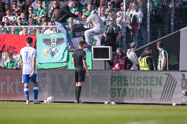 08.03.2026, Fussball, 2. Bundesliga, 25. Spieltag Saison 2025 2026, Preußen Münster - Hertha BSC, Zwei Vermummte springen über die Bande als sich Schiedsrichter Felix Bickel die Szene ansehen will, xRHR-FOTO TKx