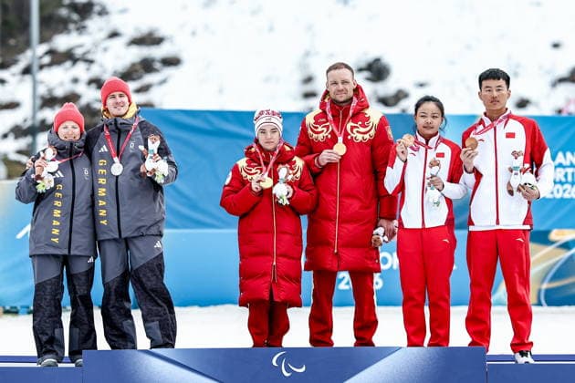 ITALY, TESERO - MARCH 10, 2026: Silver medalist Linn Kazmaier of Germany guided by Florian Baumann, gold medalist Anastasia Bagiian of Russia guided by Sergei Siniakin, and bronze medalist Jihong Cong of China guided by Jiaxuan Liu (L-R) pose during the victory ceremony for the women s para cross-country skiing classic vision impaired sprint event at Tesero Cross-Country Stadium during the 2026 Winter Paralympic Games. Mikhail Tereshchenko TASS  89851716