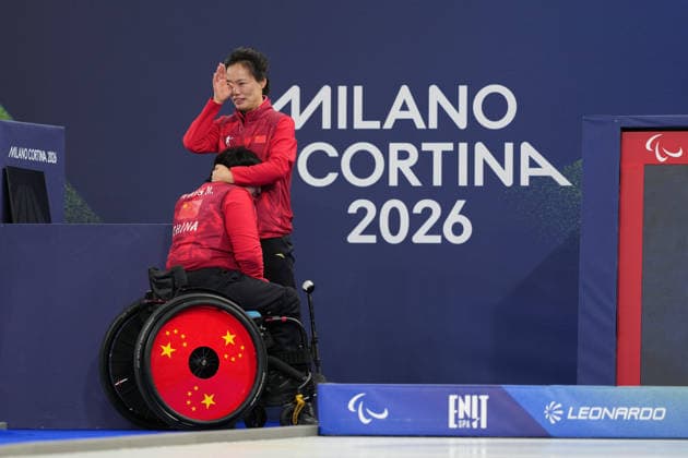 (260312) -- BEIJING, March 13, 2026 -- Coach Ru Xia (R) of China sheds tears and hugs Wang Meng after winning the wheelchair curling mixed doubles gold medal game between China and South Korea at the Milan-Cortina 2026 Paralympic Winter games, Winterspiele,Spiele, Summer games in Cortina D ampezzo, Italy, March 11, 2026. ) XINHUA PHOTOS OF THE DAY LianxYi 