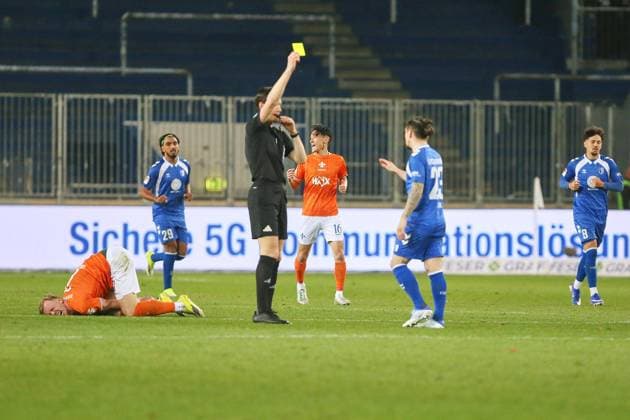 Magdeburg, Sachsen-Anhalt, Deutschland, 13.03.2026: Avnet Arena: 26. Spieltag, Saison 2025 26, 2. Fußball-Bundesliga: 1. FC Magdeburg - Darmstadt 98: Schiedsrichter Matthias Jöllenbeck zeigt die Gelbe Karte an Baris Atik (23, 1. FC Magdeburg), am Boden wälzt sich vor Schmerz Isac Lidberg (7, SV Darmstadt 98), in der Szene außerdem Rayan Ghrieb (29, 1. FC Magdeburg), Hiroki Akiyama (16, SV Darmstadt 98) und Laurin Ulrich (8, 1. FC Magdeburg)