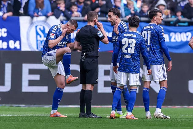 15.03.2026, Fußball, FC Schalke 04 - Hannover 96, 26. Spieltag, 2. Fußball Bundesliga, Veltins-Arena Gelsenkirchen, Saison 2025 2026: Rote Karte und Platzverweis für Edin Dzeko (Schalke04 10) nach Foulspiel. zusammen mit Kenan Karaman (Schalke04 19) gestikulierend auf dem Spielfeld neben Schiedsrichter Robin Braun DFB regulations prohibit any use of photographs as image sequences and or quasi-video. Nordrhein-Westfalen Deutschland