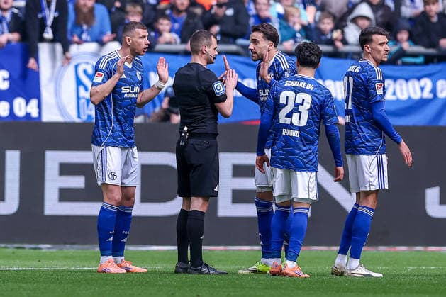 15.03.2026, Fußball, FC Schalke 04 - Hannover 96, 26. Spieltag, 2. Fußball Bundesliga, Veltins-Arena Gelsenkirchen, Saison 2025 2026: Rote Karte und Platzverweis für Edin Dzeko (Schalke04 10) nach Foulspiel. zusammen mit Kenan Karaman (Schalke04 19) gestikulierend auf dem Spielfeld neben Schiedsrichter Robin Braun DFB regulations prohibit any use of photographs as image sequences and or quasi-video. Nordrhein-Westfalen Deutschland