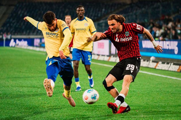 2. Bundesliga: Hannover 96 vs. Eintracht Braunschweig, 20.03.2026 Kolja Nuno Oudenne (Hannover 96, 29) flankt den Ball, Mehmet Can Aydin (Eintracht Braunschweig, 8) kommt zu spät; Fußball, 2. Bundesliga, 27. Spieltag: Hannover 96 vs. Eintracht Braunschweig am 20.03.2026 in der Heinz von Heiden Arena, Hannover DFL REGULATIONS PROHIBIT ANY USE OF PHOTOGRAPHS AS IMAGE SEQUENCES AND OR QUASI-VIDEO.