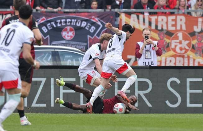 21.03.2026 - Fussball - Saison 2025 2026 - 2. Fussball - Bundesliga - 27. Spieltag: 1. FC Nürnberg FCN ( Club ) - 1. FC Kaiserslautern FCK ( Rote Roten Teufel ) - Sportfoto Zink DaMa - xdaxmax - DFL regulations prohibit any use of photographs as image sequences and or quasi-video - only for editorial use - Mika Haas (22, 1. FC Kaiserslautern FCK ) Semih Sahin (8, 1. FC Kaiserslautern FCK ) bringen Mohamed Ali Zoma (23, 1. FC Nürnberg FCN ) im Strafraum zum Elfmeter zu Fall Foul