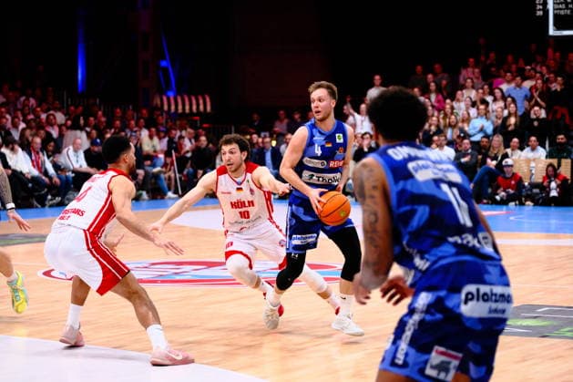 Sport Bilder des Tages ProA - RheinStars Köln vs. Phoenix Hagen, Köln, 23.03.2026, Motorworld Köln Bjarne Kraushaar ( 4, Phoenix Hagen, PG) bei der suche nach einer Anspielstation, verteidigt von Zachary Richard Watson ( 4, RheinStars Köln, PF) und Haris Hujic ( 10, RheinStars Köln, SG) ; ProA - RheinStars Köln vs. Phoenix Hagen, Köln, 23.03.2026, Motorworld Köln Copyright: xBEAUTIFULxSPORTS Piepenstockx