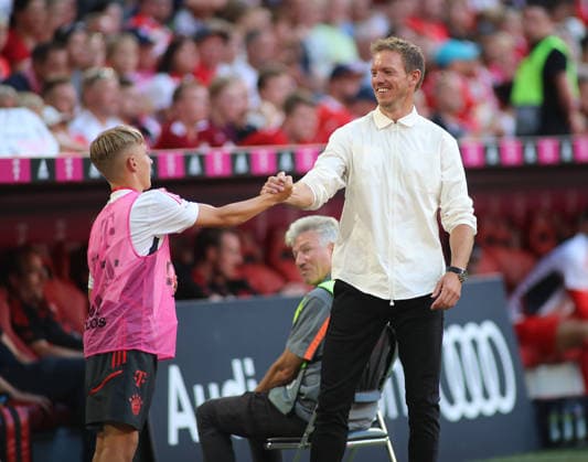 Fussball, Herren, Bundesliga, Saison 2022 2023, FC Bayern München - VFL Wolfsburg, Allianz Arena Hier im Bild der Balljunge Lennart Karl (FC Bayern München) im jungen Alter mit dem damaligen Trainer Julian Nagelsmann (FC Bayern München) an der Seitenlinie unter dem Spiel ,abklatschen, hand geben