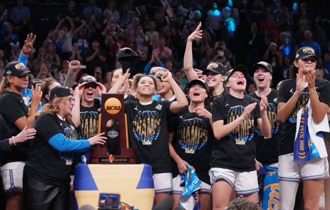 UCLA head coach Cori Close holds the trophy as players celebrate after defeating South Carolina in the Finals of the 2026 NCAA, College League, USA Women s Basketball Tournament at Mortgage Matchup Center in Phoenix, Arizona, on Sunday, April 5, 2026. UCLA defeated South Carolina 79-51 to win their first-ever women s NCAA Tournament championship.  AZP20260405974 DARRYLxWEBB