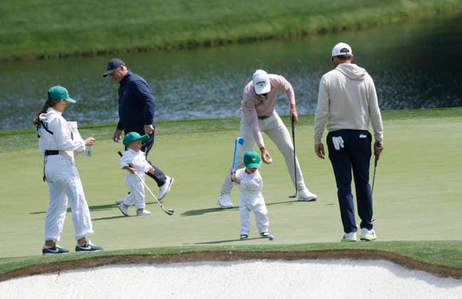 Scottie Scheffler watches his son Bennett take a swing as he and his family take part in the 2026 Masters golf tournament Par 3 Contest at Augusta National Golf Club in Augusta, Georgia, on Wednesday, April 8, 2026. The 2026 Masters Golf tournament begins on Thursday, April 9.  AUG20260408834 JOHNxANGELILLO