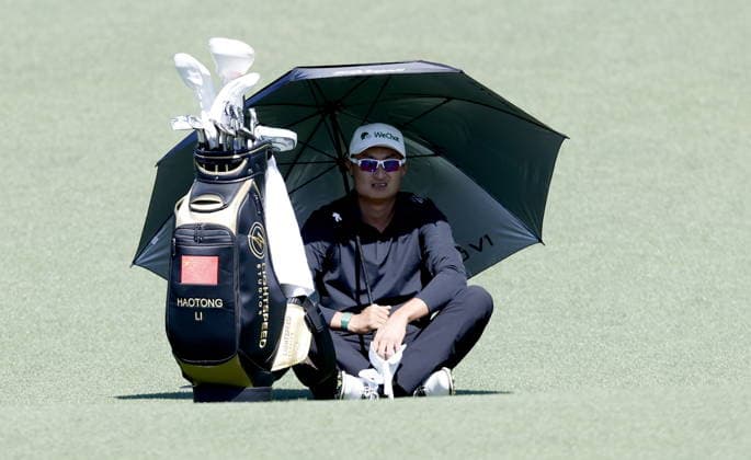 Golf 2026 Masters Tournament - Round 2 Haotong Li of China protects himself from the sun sitting next to his bag on the fairway of Hole 2 in Round 2 of the 2026 Masters tournament in August, Georgia, USA, 10 April 2026. Augusta United States  Copyright: xERIKxS.xLESSERx