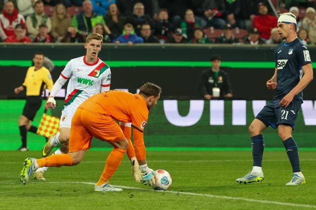 Oliver Baumann 1 (TSG 1899 Hoffenheim) greift einen Ball auf, vor Anton Kade 30 (FC Augsburg), rechts Albian Hajdari 21 (TSG 1899 Hoffenheim) , FC Augsburg vs. TSG 1899 Hoffenheim, Fussball, Maenner, Bundesliga, Saison 2025 2026, Rueckrunde, 29. Spieltag, 10.04.2026 DFB regulations prohibit any use of photographs as image sequences and or quasi-video Augsburg Bayern Deutschland *** Oliver Baumann 1 TSG 1899 Hoffenheim picks up a ball, in front Anton Kade 30 FC Augsburg , right Albian Hajdari 21 TSG 1899 Hoffenheim , FC Augsburg vs TSG 1899 Hoffenheim, Football, Men, Bundesliga, Season 2025 2026, Second round, Matchday 29, 10 04 2026 DFB regulations prohibit any use of photographs as image sequences and or quasi video Augsburg Bayern Germany Copyright: xkolbert-press MartinxAgüerax