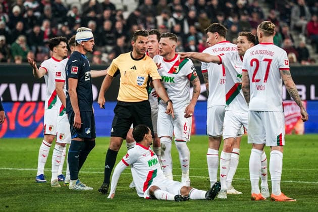 Fussball: Deutschland: 1. Bundesliga 2025 2026 - 29. Spieltag, 10.04.2026 - FC Augsburg vs. TSG Hoffenheim - WWK Arena (Augsburg, Deutschland); Diskussionen zwischen Schiedsrichter Daniel Schlager und Jeffrey Gouweleeuw (FC Augsburg) *** Soccer Germany 1 Bundesliga 2025 2026 Matchday 29, 10 04 2026 FC Augsburg vs TSG Hoffenheim WWK Arena Augsburg, Germany Discussions between referee Daniel Schlager and Jeffrey Gouweleeuw FC Augsburg Copyright: xLUKAxKOLANOVICx
