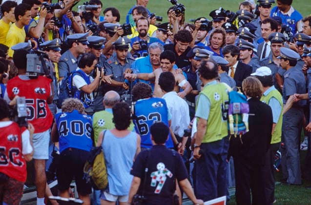 WM 1990 - Viertelfinale - Argentinien vs Jugoslawien, Diego Maradona (ARG) WM 1990 in Italien, Stadio Artemio Franchi in Florenz, Viertelfinale: Argentinien vs Jugoslawien 3:2 nach Elfmeterschießen. Diego Maradona (Argentinien) wird nach dem Spiel von Polizisten und Ordnern vom Spielfeld eskortiert, umringt von Fotografen. Florence Italy *** World Cup 1990 Quarter-finals Argentina vs Yugoslavia, Diego Maradona ARG World Cup 1990 in Italy, Stadio Artemio Franchi in Florence, Quarter-finals Argentina vs Yugoslavia 3 2 After Penalty shootout Diego Maradona Argentina will After the Game from Policemen and Folders of Playing field escorted, surrounded from Photographers Florence Italy Copyright: xUnitedxArchivesx xSvenxSimonxSportx SVS_95020000589