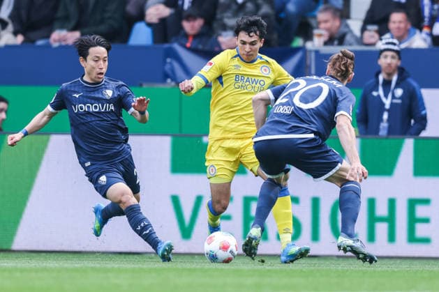 Fußball 2. Bundesliga 29. Spieltag VfL Bochum - Eintracht Braunschweig am 12.04.2026 im Vonovia Ruhrstadion in Bochum Koji Miyoshi ( Bochum ), links - Johan Gomez ( Braunschweig ), mitte . Noah Loosli ( Bochum ), rechts DFL regulations prohibit any use of photographs as image sequences and or quasi-video.