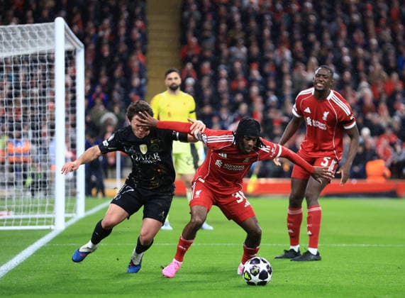 Liverpool, England, 14th April 2026. Joao Neves of Paris St Germain tussles with Jeremie Frimpong of Liverpool tussles with during the Liverpool vs Paris Saint Germain UEFA Champions League quarter final 2nd leg match at Anfield, Liverpool. Picture credit should read: Jessica Hornby Sportimage EDITORIAL USE ONLY. No use with unauthorised audio, video, data, fixture lists, club league logos or live services. Online in-match use limited to 120 images, no video emulation. No use in betting, games or single club league player publications. SPI_063_JH_Liverpool_PSG SPI-4687-0063