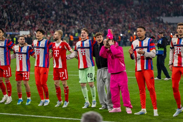 15.04.2026, Fussball UEFA Championsleague 2025 2026: Viertelfinale Rückspiel, FC Bayern München - Real Madrid, in der Allianz-Arena München,Schlussjubel nach dem 4:3, die Spieler in der Fankurve. Min-jae Kim (Bayern München, Minjae Kim), Konrad Laimer (FC Bayern München), Torwart Jonas Urbig (FC Bayern München), Tom Bischof (Bayern München), Lennart Karl (FC Bayern München), Torwart Leonard Prescott (FC Bayern München) und Filip Pavic (FC Bayern München), Leon Goretzka (FC Bayern München), Torwart Manuel Neuer (FC Bayern München), Luis Diaz (FC Bayern München), Bildserie: Tom Bischof (Bayern München) klaut Lennart Karl (FC Bayern München) die pinke Mütze vom Kopf.