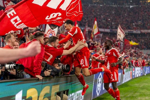 15.04.2026, Fussball UEFA Championsleague 2025 2026: Viertelfinale Rückspiel, FC Bayern München - Real Madrid, in der Allianz-Arena München, Fans stürmen vor Abpfiff den Innenraum und drücken beim Torjubel die Banden mit den Fotografen um, zwei Fotografen werden verletzt, sogar bewusstlos, und müssen danach nötärztlich versorgt werden. Jamal Musiala (Bayern München) springt auf das Menschenknäuel. re: Dayot Upamecano (FC Bayern München) *** 15 04 2026, Football UEFA Champions League 2025 2026 quarter-final second leg, FC Bayern Munich Real Madrid, in the Allianz Arena Munich, fans storm the interior before the final whistle and push over the boards with the photographers while celebrating the goal, two photographers are injured, even unconscious, and have to be treated by a doctor afterwards Jamal Musiala Bayern Munich jumps on the crowd re Dayot Upamecano FC Bayern Munich