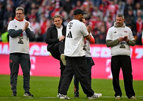 19.04.2026, Fussball Bundesliga 2025 2026, 30.Spieltag, FC Bayern München - VfB Stuttgart, in der Allianz-Arena München, v.l. x, Sportdirektor Christoph Freund (Bayern München), x, Trainer Vincent Kompany (FC Bayern München) und x feiern mit Meister Kakadu T-Shirt. Sportdirektor Christoph Freund (Bayern München) gibt Trainer Vincent Kompany (FC Bayern München) einen Tritt