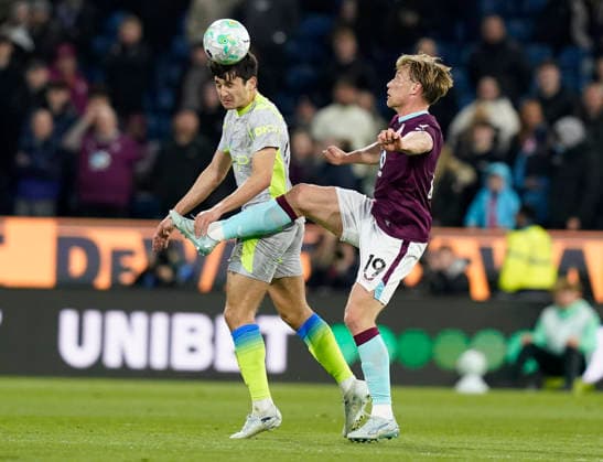 Burnley, England, 22nd April 2026. Abdukodir Khusanov of Manchester City (L) heads clear from Zian Flemming of Burnley during the Burnley vs Manchester City Premier League match at Turf Moor, Burnley. Picture credit should read: Andrew Yates Sportimage EDITORIAL USE ONLY. No use with unauthorised audio, video, data, fixture lists, club league logos or live services. Online in-match use limited to 120 images, no video emulation. No use in betting, games or single club league player publications. SPI_024_AY_BURNLEY_MAN_CITY SPI-4716-0024