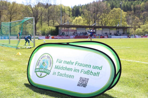 Sachsenpokal-Finale Frauen: Chemnitzer FC - RB Leipzig II; 01.05.2026 Werbung, Öffentlichkeitsarbeit, Aufsteller für mehr Frauen und Mädchen im Fußball - mit dem Spielfeld und Tribüne im Hintergrund. Symbolbild, Feature. Sachsenpokal-Finale der Frauen Sachsenlotto-Landespokal: Chemnitzer FC vs. RB Leipzig II U20 im Auenstadion Flöha, 01.05.2026. Copyright: xBEAUTIFULxSPORTS JanxKaeferx