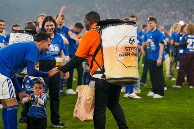 Deutschland: Fussball 2. Bundesliga 2025 - 2026, 32. Spieltag - FC Schalke 04 vs Fortuna Düsseldorf - Veltins Arena (Schalke): Kenan Karaman (Schalke 04, 19) Bierverkäufer, Veltins Pils, Maskottchen Erwin, Platz, Aufstieg, Feier, Emotionen, Fußball, 2. Bundesliga, Spieler, Fans, Fahne, Vereinsfarben blau-weiß, Stadionatmosphäre, Jubel, Event, Sportfotografie, Medienbild