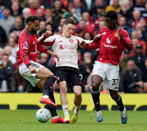 Manchester, England, 3rd May 2026. Florian Wirtz of Liverpool (c) tackled by Matheus Cunha of Manchester United, ManU (l) and Kobbie Mainoo of Manchester United (r) during the Manchester United vs Liverpool Premier League match at Old Trafford, Manchester. Picture credit should read: Andrew Yates Sportimage EDITORIAL USE ONLY. No use with unauthorised audio, video, data, fixture lists, club league logos or live services. Online in-match use limited to 120 images, no video emulation. No use in betting, games or single club league player publications. SPI_055_AY_MAN_UTD_LIVERPOOL SPI-4776-0054