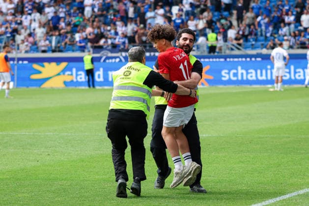 Deutschland: Karlsruher SC vs. SV Darmstadt 98, 32. Spieltag, 2. Bundesliga, Saison 2025 26, BBBank Wildpark (Karlsruhe): Junger Fan Flitzer auf dem Feld nach dem Spiel im Türkei Trikot von Kenan Yildiz Kenan YÄ±ldÄ±z (türkischer Nationalspieler), Securitys versuchen ihn zu fangen zu stoppen Karlsruhe BBBank Wildpark Baden-Württemberg Deutschland