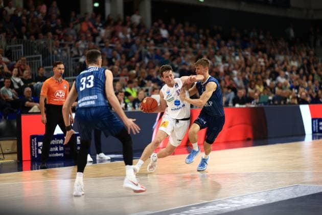 Niklas Würzner (2; MLP Academics Heidelberg) dribbelt energisch, während Spencer Reaves (31; Syntainics MBC) ihn verteidigt im SNP Dome Dribbling und Verteidigung im SNP Dome Copyright: xMichaelxGelhardtx