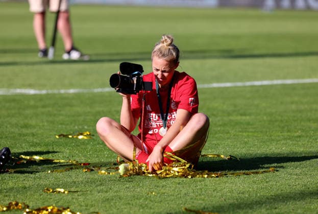 Fussball, Frauen, Google Pixel Frauen Bundesliga, 25.Spieltag, Saison 2025 2026, FC Bayern München - Eintracht Frankfurt, Campus Die Meisterfeier nach dem Spiel, hier die Mannschaft des FC Bayern München Frauen, hier Carolin Simon (FC Bayern München) sitzend auf dem Spielfeld mit einer Videokamera in der Hand