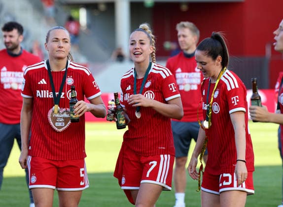 Fussball, Frauen, Google Pixel Frauen Bundesliga, 25.Spieltag, Saison 2025 2026, FC Bayern München - Eintracht Frankfurt, Campus Die Meisterfeier nach dem Spiel, hier die Mannschaft des FC Bayern München Frauen, hier Magdalena Eriksson (FC Bayern München) mit Giulia Gwinn (FC Bayern München) und Sarah Zadrazil (FC Bayern München) (v.l.n.r.) mit Lebkuchenherz und Medaille sowie Radlerbier