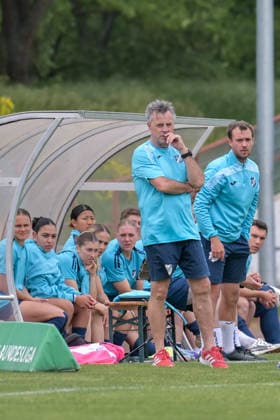 10.05.2026, Fußball, 2. Frauen-Bundesliga, 2025 2026, 25. Spieltag, SG 99 Andernach - SC Sand Cheftrainer Alexander Fischinger (Sand) schaut während des Spiels skeptisch drein. Auch die Ersatzspielerinnen sind noch nicht überzeugt. Andernach Stadion Rheinland-Pfalz Deutschland