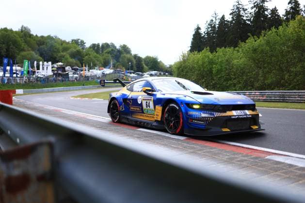 Der Christopher Mies & Dennis Olsen & Emil Christian Gjerdrum & Finn Wiebelhaus & Frederic Vervisch (HRT Ford Racing) Ford Mustang GT3 mit der Startnummer 64 von HRT Ford Racing durchfährt eine Kurve auf dem Nürburgring. Das Fahrzeug trägt eine markante blau-goldene Lackierung mit RAVENOL- und DEKRA-Sponsoring sowie dem Schriftzug Ford Racing und Haupt Racing Team . Im Hintergrund sind die charakteristischen Leitplanken, grüne Vegetation und die Zuschauerinfrastruktur des Nürburgrings zu erkennen. Ford Mustang GT3 64 von HRT Ford Racing auf dem Nürburgring *** The Christopher Mies Dennis Olsen Emil Christian Gjerdrum Finn Wiebelhaus Frederic Vervisch HRT Ford Racing Ford Mustang GT3 with the starting number 64 from HRT Ford Racing drives through a corner on the Nürburgring The vehicle wears a striking blue and gold livery with RAVENOL and DEKRA sponsorship as well as the Ford Racing and Haupt Racing Team lettering The characteristic crash barriers, green vegetation and the spectator infrastructure of the Nürburgring can be seen in the background Ford Mustang GT3 64 from HRT Ford Racing on the Nürburgring Copyright: xMichaelxGelhardtx