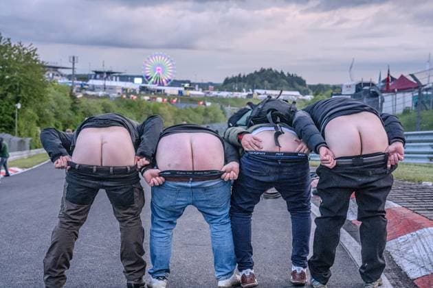 Vier Fans präsentieren am Nürburgring einen klassischen Mooning -Moment direkt auf dem Asphalt der Rennstrecke. Im Hintergrund ist das beleuchtete Riesenrad des Fahrerlagers sowie die Infrastruktur des Eventgeländes zu erkennen. Die ausgelassene Stimmung spiegelt die einzigartige Atmosphäre des 24h-Rennwochenendes wider. Fans zeigen ihren Hintern auf der Strecke am Nürburgring *** Four fans present a classic mooning moment directly on the asphalt of the race track at the Nürburgring The illuminated Ferris wheel of the paddock and the infrastructure of the event site can be seen in the background The exuberant mood reflects the unique atmosphere of the 24-hour race weekend Fans show off their butts on the track at the Nürburgring Copyright: xMichaelxSchäferx
