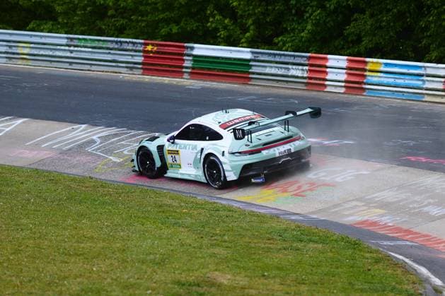 Der Porsche 911 GT3 R mit der Startnummer 24 von Lionspeed GP durchfährt eine Kurve auf der Nordschleife des Nürburgrings beim ADAC RAVENOL 24h Nürburgring 2026. Das Fahrzeug im mintgrünen Design mit Wempe- und H&R-Sponsoring nimmt die mit bunten Graffiti-Botschaften der Fans versehene Curb-Zone. Laurens Vanthoor & Laurin Heinrich & Ricardo Feller (Lionspeed GP) Porsche 911 GT3 R 24 von Lionspeed GP auf der Nordschleife