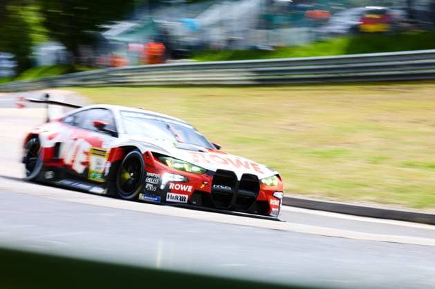 Der BMW M4 GT3 von ROWE RACING mit der Startnummer 99 durchfährt mit hoher Geschwindigkeit einen Streckenabschnitt auf der Nordschleife am Nürburgring. Das Fahrzeug in der markanten rot-weißen ROWE-Lackierung ist mit Sponsoren wie H&R, Michelin, Synopsys und Endless ausgestattet. Die Panning-Aufnahme unterstreicht die Dynamik des Rennfahrzeug beim ADAC RAVENOL 24h Nürburgring 2026. ROWE RACING BMW M4 GT3 99 auf der Nordschleife