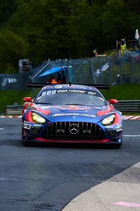 Der Mercedes-AMG GT3 mit der Startnummer 3 des Mercedes-AMG Team Verstappen Racing nähert sich frontal der Kamera auf der Nordschleife am Nürburgring. Das Fahrzeug trägt ein markantes blau-rotes Red Bull Livery mit AMG- und Gran Turismo-Sponsoring und leuchtet mit seinen eingeschalteten Scheinwerfern auf dem nassen Asphalt. Sparco- und H&R-Logos sind an der Fahrzeugfront deutlich erkennbar. Daniel Juncadella & Jules Gounon & Lucas Auer & Max Verstappen (Mercedes-AMG Team Verstappen Racing) Mercedes-AMG GT3 3 von Verstappen Racing auf der Nordschleife