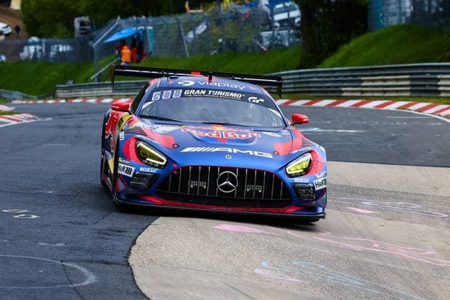 Der Mercedes-AMG GT3 mit der Startnummer 3 des Mercedes-AMG Team Verstappen Racing durchfährt eine Kurve auf der Nordschleife am Nürburgring. Das Fahrzeug Daniel Juncadella & Jules Gounon & Lucas Auer & Max Verstappen (Mercedes-AMG Team Verstappen Racing) trägt das markante Red-Bull-Livery in Blau, Rot und Gold und ist mit Sponsoren wie Viaplay, Gran Turismo und AMG prominent beklebt. Die gelben Scheinwerfer und der große Heckflügel unterstreichen den GT3-Renncharakter des Fahrzeugs. Mercedes-AMG GT3 3 von Verstappen Racing auf der Nordschleife