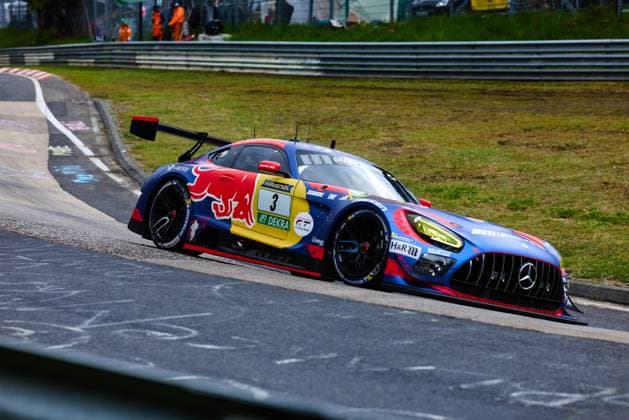 Der Mercedes-AMG GT3 mit der Startnummer 3 des Mercedes-AMG Team Verstappen Racing nimmt eine enge Kurve auf der Nordschleife am Nürburgring. Das Fahrzeug trägt ein auffälliges Red-Bull-Livery in Blau und Rot mit RAVENOL- und DEKRA-Sponsoring. Daniel Juncadella & Jules Gounon & Lucas Auer & Max Verstappen (Mercedes-AMG Team Verstappen Racing) bewältigt den Kurvenausgang souverän auf dem charakteristischen Asphalt der Nordschleife. Mercedes-AMG GT3 3 von Verstappen Racing auf der Nordschleife
