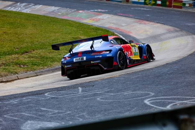 Der Mercedes-AMG GT3 mit der Startnummer 3 des Mercedes-AMG Team Verstappen Racing durchfährt eine Kurve auf der Nordschleife am Nürburgring. Das in Blau gehaltene Fahrzeug Daniel Juncadella & Jules Gounon & Lucas Auer & Max Verstappen (Mercedes-AMG Team Verstappen Racing) ist mit den Sponsoren Red Bull, H&R und Michelin beklebt und zeigt die typische GT3-Aerodynamik mit markanter Heckpartie und großem Heckflügel. Auf dem Randstein und dem Streckenbelag sind charakteristische Kreidemarkierungen der Fans zu sehen. Mercedes-AMG GT3 3 von Verstappen Racing auf der Nordschleife