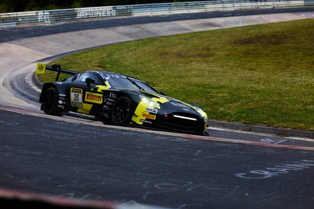 Der Aston Martin GT3 mit der Startnummer 35 von Walkenhorst Motorsport durchfährt eine Kurve auf der Nordschleife des Nürburgrings. Das schwarz-gelbe Fahrzeug Dennis Fetzer & Felipe Fernandez Laser & Mateo Villagoméz & Stefan Aust (Walkenhorst Motorsport) ist mit Sponsoren wie RAVENOL, Pirelli, DEKRA und H&R ausgestattet und zeigt die charakteristischen AMR-Logos. Im Hintergrund sind die typischen Gr NFL, American Football Herren, USA chen und Curbs der Nordschleife zu sehen. Aston Martin 35 von Walkenhorst Motorsport auf der Nordschleife