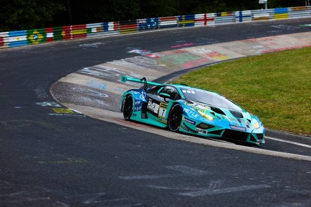 Der Lamborghini Huracán GT3 mit der Startnummer 7 von Konrad Motorsport durchfährt eine enge Kurve auf der Nordschleife des Nürburgrings. Das in türkis-schwarz gehaltene Fahrzeug Christian Engelhart & Maximilian Paul & Patricija Stalidzane & Pavel Lefterov (Konrad Motorsport) trägt Sponsoren wie H&R, RAVENOL, MEYLE und Michelin und zeigt die charakteristischen bunten Fangzäune der Nordschleife im Hintergrund. Lamborghini Huracán GT3 7 von Konrad Motorsport auf der Nordschleife