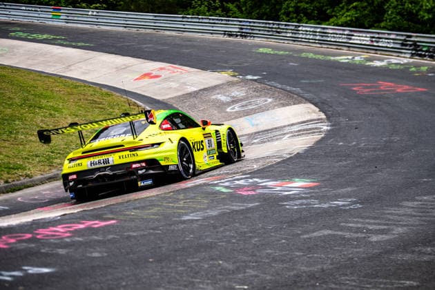 Manthey ( 911) SP 9. Ein gelb-grüner Porsche 911 GT3 R mit Werbeaufschriften fährt eine Kurve der Nürburgring-Nordschleife entlang. Rheinland-Pfalz Deutschland