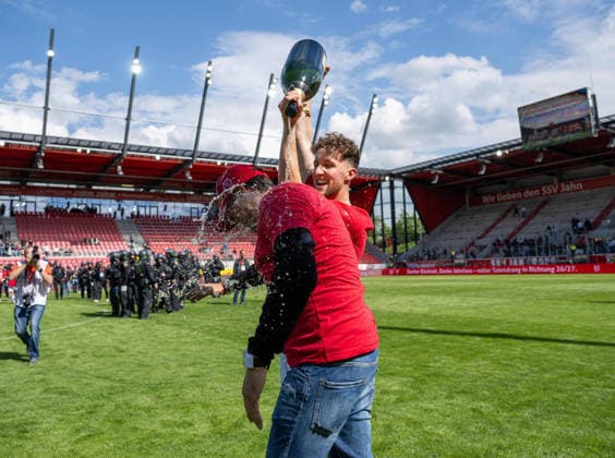 Fussball, Herren, Saison 2025 2026, 3. Liga (38. Spieltag), SSV Jahn Regensburg - FC Energie Cottbus, Champagner-Dusche von Tim Campulka (Energie Cottbus) an Trainer Claus-Dieter Pele Wollitz (Energie Cottbus), 16.05. 2026, Copyright: xSebastianxRäppold MatthiasxKochx