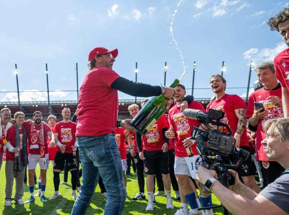 Fussball, Herren, Saison 2025 2026, 3. Liga (38. Spieltag), SSV Jahn Regensburg - FC Energie Cottbus, Trainer Claus-Dieter Pele Wollitz (Energie Cottbus) und seine Spieler feiern nach Abpfiff mit Champagner, 16.05. 2026, Copyright: xSebastianxRäppold MatthiasxKochx