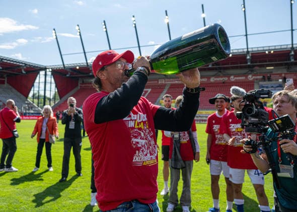 Fussball, Herren, Saison 2025 2026, 3. Liga (38. Spieltag), SSV Jahn Regensburg - FC Energie Cottbus, Trainer Claus-Dieter Pele Wollitz (Energie Cottbus), Jubel nach Abpfiff mit Champagner, 16.05. 2026, Copyright: xSebastianxRäppold MatthiasxKochx
