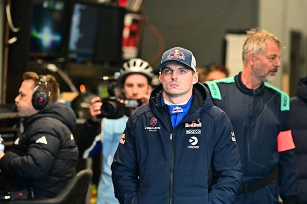 Max Verstappen steht konzentriert in der Box oder im Fahrerlager am Nürburgring. Er trägt eine Red-Bull-Cap und eine Jacke mit den Logos von Verstappen Racing, Red Bull, Sparco und Viaplay. Im Hintergrund sind Teammitglieder, ein Kameramann sowie Monitore zu sehen. Max Verstappen im Fahrerlager beim 24h Nürburgring 2026 Copyright: xMichaelxGelhardtx