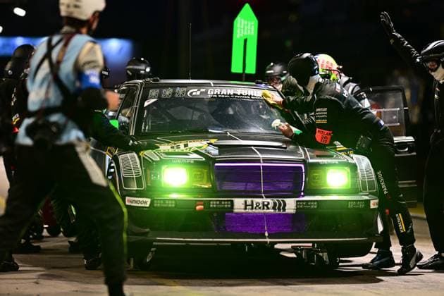 Das Fahrzeug Rennfahrzeug von Hofor Racing by Bonk Motorsport absolviert einen nächtlichen Boxenstopp an der Nürburgring-Boxengasse. Die Mechaniker reinigen die Windschutzscheibe und betreuen das dunkelgrün lackierte Fahrzeug, dessen markante grüne und violette Beleuchtung die nächtliche Atmosphäre unterstreicht. Deutlich sichtbare Sponsoren sind H&R, Wempe, Hankook, Kärcher und Parkside. Das Pitlane-Schild mit der Nummer 132 ist an der Fahrzeugseite befestigt. Nächtlicher Boxenstopp beim 24h Nürburgring – Hofor Racing 189 Copyright: xMichaelxGelhardtx