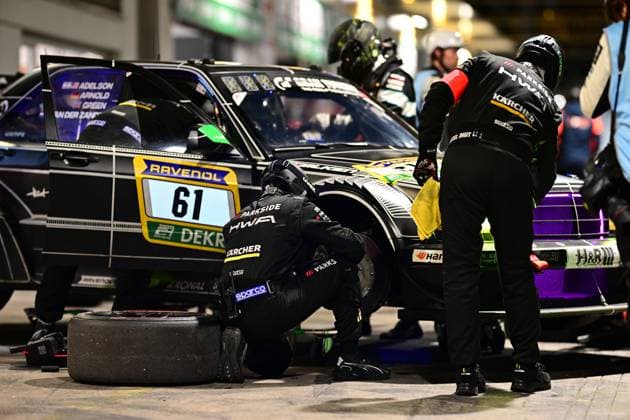 Der Bruno Spengler & Christian Gebhardt & Evald Holstad & Peter Ludwig (HWA Engineering Speed) von HWA Engineering Speed absolviert in der Nacht einen Boxenstopp am Nürburgring. Mechaniker in schwarzen Overalls mit HWA- und Kärcher-Logos arbeiten konzentriert am Fahrzeug: Einer kniet am Vorderrad und führt den Reifenwechsel durch, ein abgenutzter Reifen liegt bereits auf dem Boxenasphalt. Ein weiterer Mechaniker reinigt die Fahrzeugfront mit einem gelben Tuch. Auf der Fahrertür sind die Fahrernamen Adelson, Arnold, Green und Van der Zande aufgelistet. Sponsoren wie RAVENOL, Sparco, Parkside und Kärcher sind deutlich sichtbar. Nacht-Boxenstopp: 61 von HWA Engineering Speed am Nürburgring Copyright: xMichaelxGelhardtx