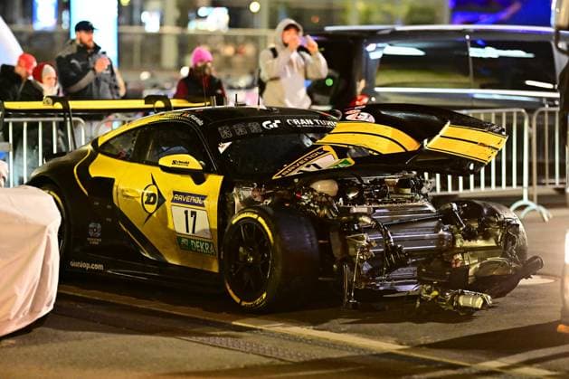 Das Alessio Picariello & Dorian Boccolacci & Julien Andlauer & Nico Menzel (Dunlop Motorsport) von Dunlop Motorsport steht nach einem schweren Unfall am Nürburgring. Die gesamte Front des schwarz-gelben GT3-Fahrzeugs ist komplett abgerissen – Motor, Antriebsstrang und Fahrwerkskomponenten liegen freigelegt auf dem Asphalt. Die Motorhaube steht offen, der Heckflügel ist ebenfalls beschädigt. Sponsoren wie RAVENOL, DEKRA und Gran Turismo sind auf der Karosserie sichtbar. Zahlreiche Zuschauer im Hintergrund beobachten und fotografieren die Unfallszene in der Nacht. Schwer beschädigter 17 Dunlop Motorsport GT3 am Nürburgring Copyright: xMichaelxGelhardtx